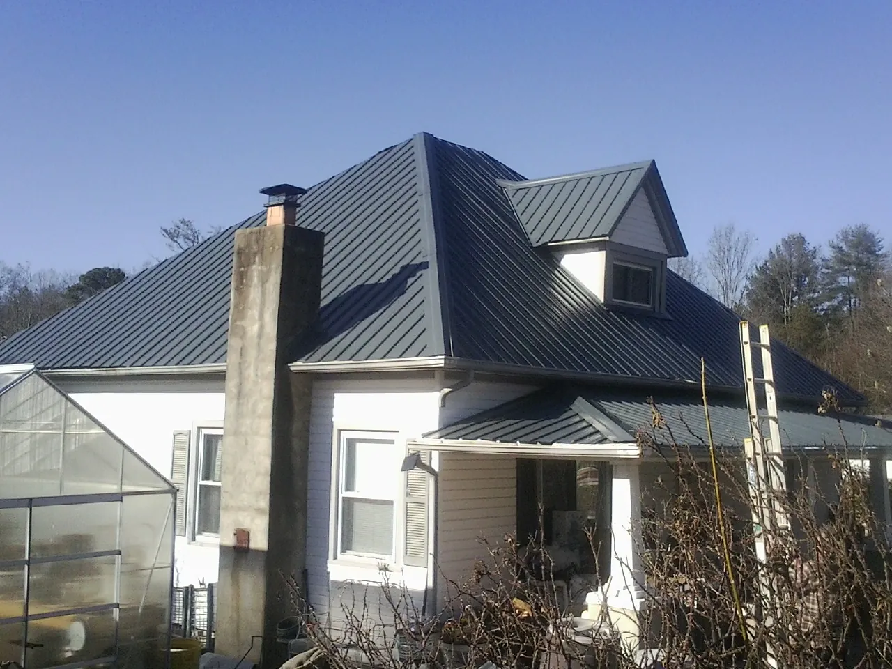 Dark blue standing seam metal roof on a white farmhouse with dormer — Slate & Tile Roof Repair by Roofing Brothers in Cockeysville