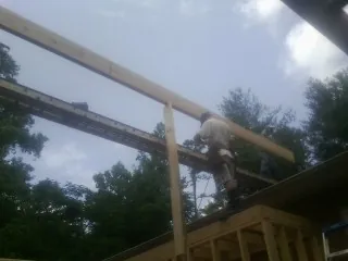 Carpenter setting a ridge beam over a new addition frame — Ice Dam Removal by Roofing Brothers in Cockeysville