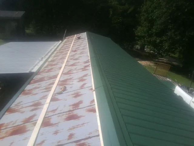 Old rusted panels beside newly installed green metal roofing — Wind Damage Roof Repair by Roofing Brothers in Cockeysville