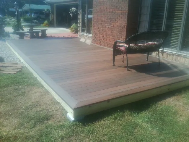New wood deck and wicker chair beside a brick house in Cockeysville
