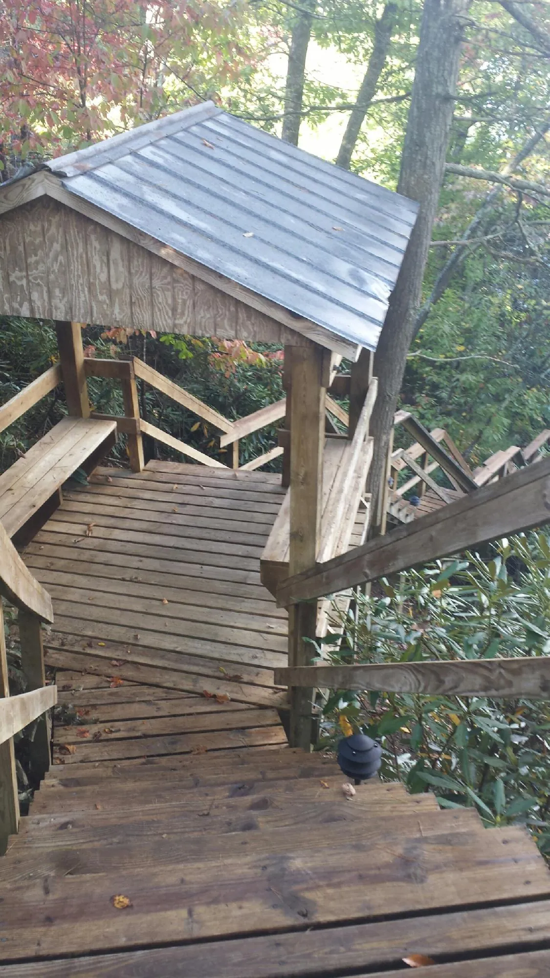 Metal roofed shelter over wooden steps on a wooded walkway — Skylight Repair & Installation work by our crew in Cockeysville