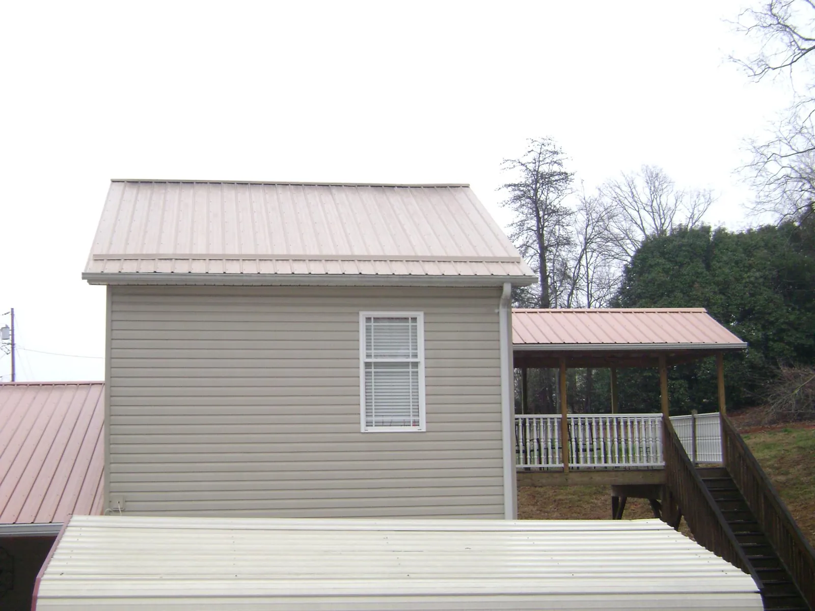 Tan metal roofs on a two story addition and attached porch, from a Roof Replacement job in Cockeysville