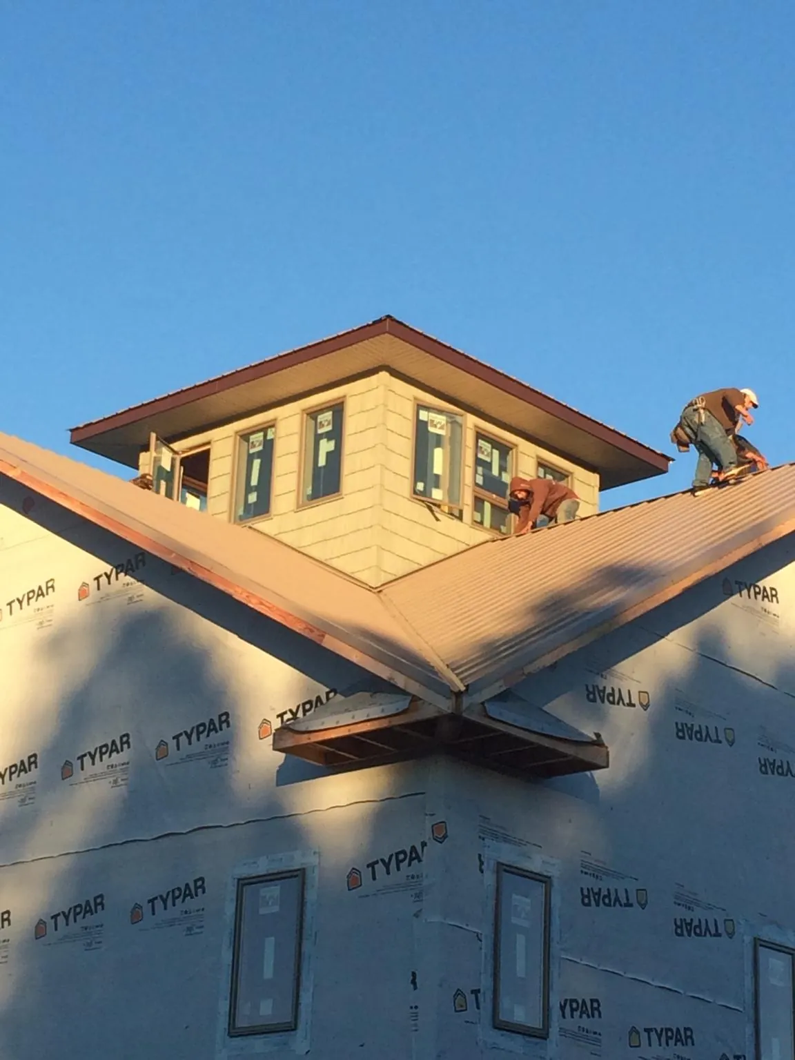 Roofers working around a rooftop cupola on a new metal roof at sunset — Roof Waterproofing in Cockeysville by Roofing Brothers